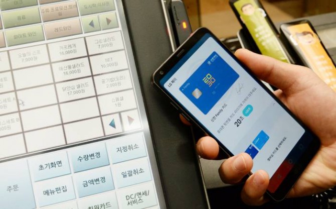 스토랑 종업원이 신용카드 대신 LG페이가 작동 중인 LG G6를 LG전자 직원으로부터 건내받아 마그네틱 단말기에 가져가 결제를 진행하고 있다. - LG전자 제공
