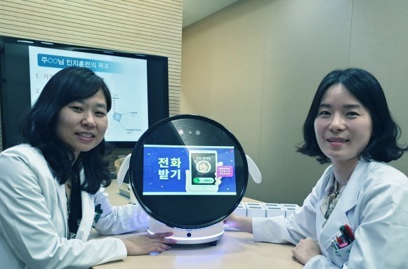 김건하 이대목동병원 신경과 교수(왼쪽)가 로보케어와 공동 개발한 인지 훈련 로봇 ′보미′을 선보이고 있다. 나연아 신경심리사 지도하에 환자와 1대1로 인지훈련을 할 수 있다.