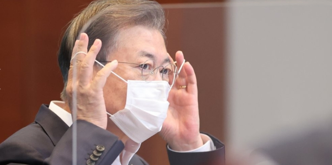 문재인 대통령이 24일 오후 청와대에서 열린 수석·보좌관 회의에서 발언에 앞서 마스크를 벗고 있다. 신종 코로나바이러스 감염증(코로나19) 2차 대유행 우려가 커지면서 이날 회의에는 평소보다 적은 참석자들이 유리벽을 사이에 두고 떨어져 앉아 앉아 회의를 했다. 연합뉴스