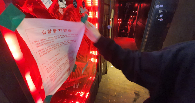 12일 새벽 서울 한 클럽에서 관계자가 집합금지 안내문을 떼고 있다. 정부는 이날부터 코로나19 방역 대응 사회적 거리두기를 2단계에서 1단계로 조정했다. 수도권의 경우 ▲ 클럽·룸살롱 등 유흥주점 ▲ 콜라텍 ▲ 단란주점 ▲ 감성주점 ▲ 헌팅포차 ▲ 노래연습장 ▲ 실내 스탠딩 공연장 ▲ 실내집단운동(격렬한 GX류) ▲ 뷔페 ▲ 대형학원(300인 이상) 등 10종의 고위험시설에 대한 집합금지 조처가 해제됐다. 연합뉴스 제공