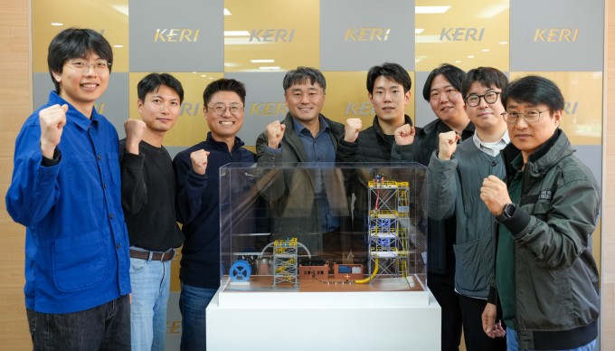 최진욱 한국전기연구원 전력케이블연구센터 책임연구원(왼쪽에서 네 번째) 연구팀이 J-tubeless 해저케이블 설치 공법을 설명하는 모형 앞에서 기념 촬영을 하고 있다. 전기연 제공