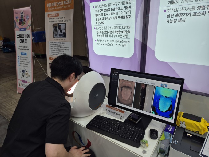 A visitor puts their face up to the artificial intelligence (AI) tongue diagnosis device at the Korea Institute of Oriental Medicine booth. A camera photographs the tongue, and an AI analyzes its color, shape, and coating to output a reference result on their health status. By Lim Jeong-woo, jjwl@donga.com