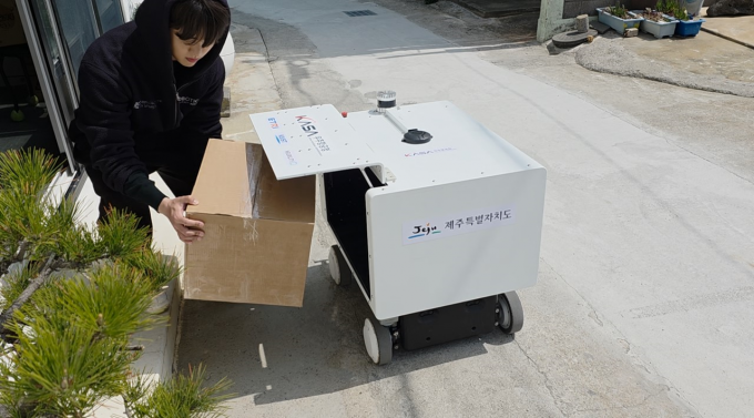 An autonomous delivery robot unloads cargo at a delivery point on Biyangdo Island, Jeju. Courtesy of KASA