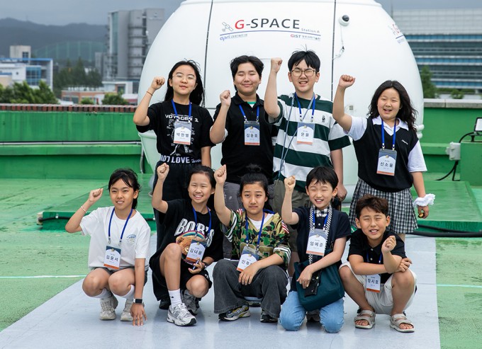 The Children's Space Reporters pose for a commemorative photo in front of the laser communication ground station. Provided by Studio51