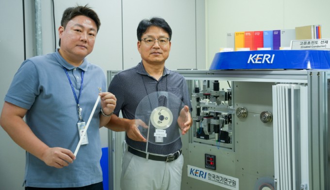 왼쪽부터 박인성 한국전기연구원 선임연구원과 하홍수 책임연구원이 고온초전도 선재를 들고 3D 비접촉 초정밀 검사 장비 옆에 서있다. 전기연 제공